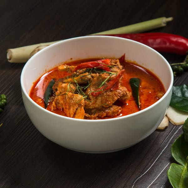 Spice Zone Indian Restaurant's chicken curry in a white bowl, garnished with red chilies and herbs.