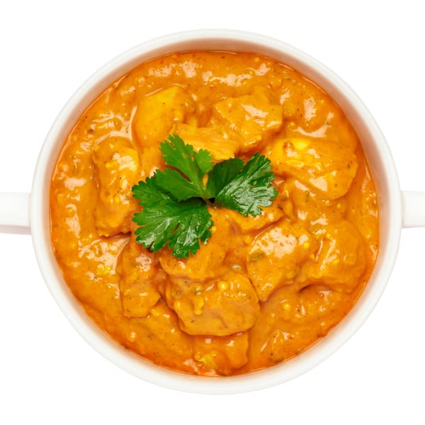 Overhead view of a white bowl filled with orange Indian chicken curry, garnished with fresh cilantro.