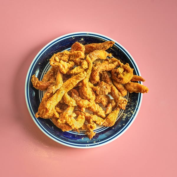 Crispy fried chicken skin or pork belly strips, seasoned with spices, on a blue and white plate.